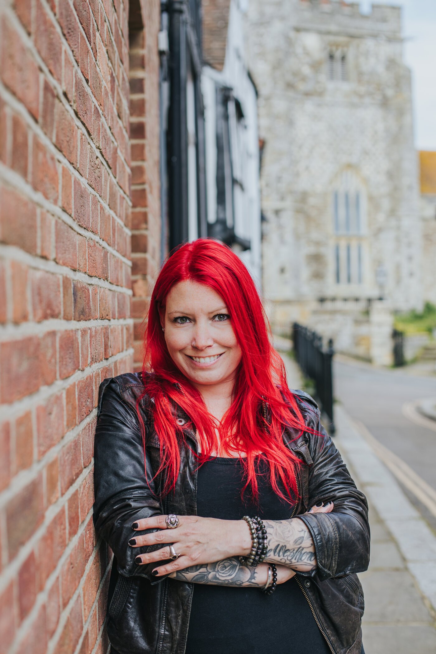 Ronia Fraser, portrait, leaning against a brick wall